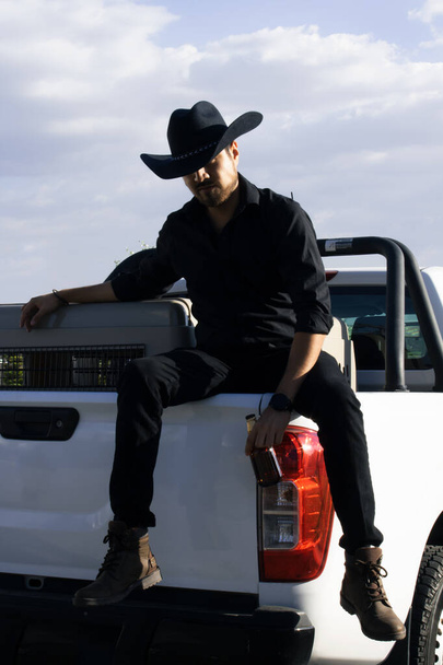 cowboy sitting on his truck drinking beer - Фото, изображение