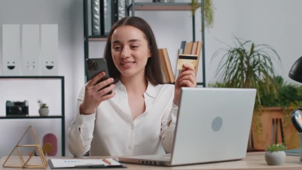 Mutlu iş kadını programcı yazılım geliştirici ev ofis masasında dizüstü bilgisayarla kredi kartı kullanarak online satın alma alışverişi yapıyor. Kafkasyalı serbest kız. - Video, Çekim