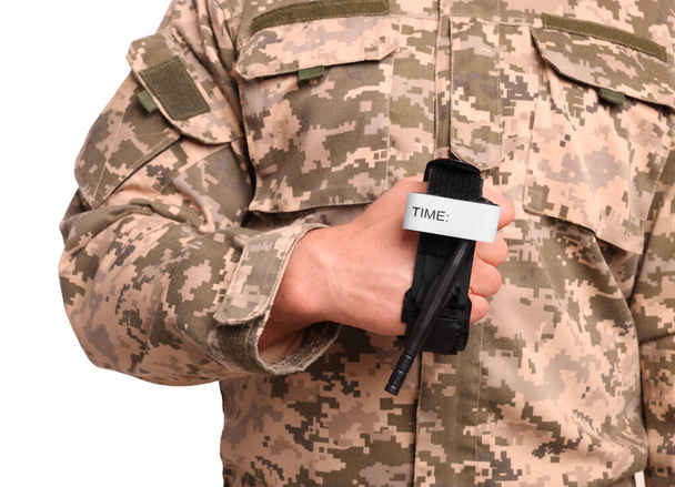 Soldier in military uniform holding medical tourniquet on white background, closeup - Zdjęcie, obraz