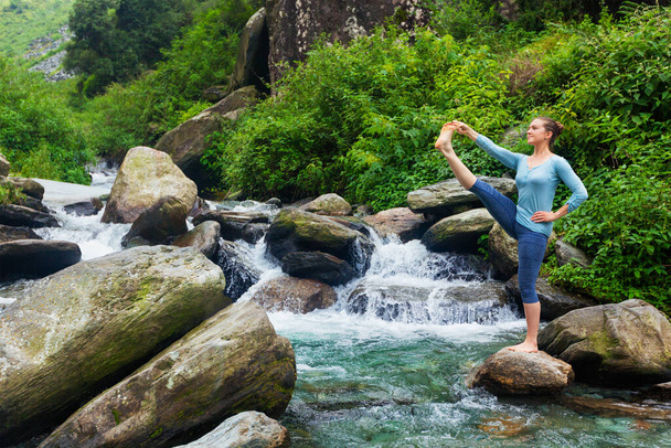 Yoga en plein air - femme faisant Ashtanga Vinyasa Yoga balance asana Utthita Hasta Padangushthasana - posture de posture étendue de la main aux gros orteils à la cascade
 - Photo, image