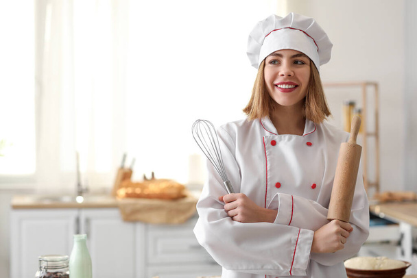 Женщина-пекарь со скалкой и венчиком на кухне - Фото, изображение