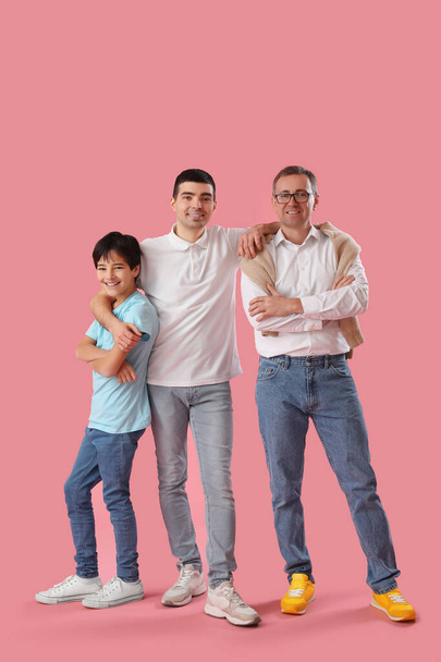 Щасливий маленький хлопчик з батьком і дідом на рожевому фоні - Фото, зображення