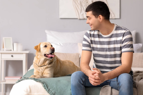 Giovane con cane Labrador in camera da letto - Foto, immagini