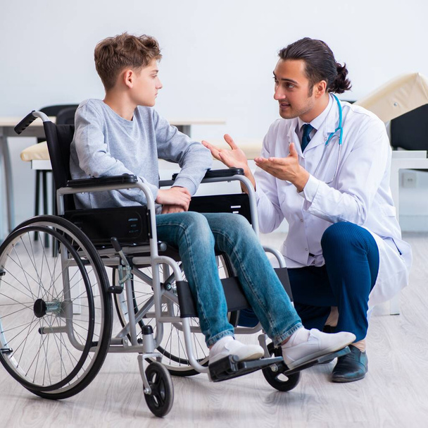 Mladý lékař pediatr a chlapec na kolečkovém křesle - Fotografie, Obrázek
