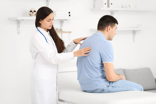 Femme médecin vérifier la posture du jeune homme à la clinique - Photo, image
