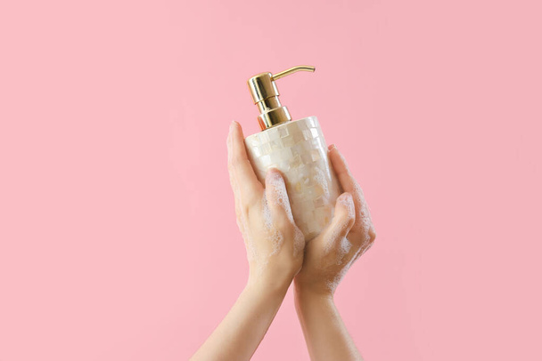 Handen met vloeibare zeep op roze achtergrond - Foto, afbeelding
