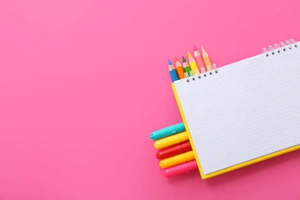 Blanko-Notizbuch mit verschiedenen bunten Markern und Bleistiften auf rosa Hintergrund - Foto, Bild