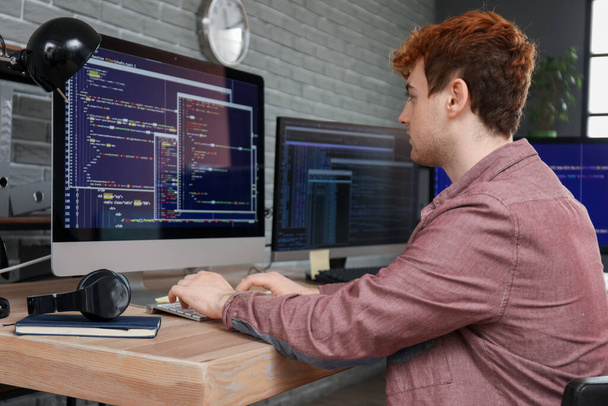 Programador masculino trabajando con el ordenador en la mesa en la oficina - Foto, Imagen