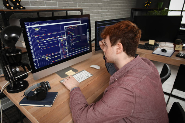 Mies ohjelmoija työskentelee tietokoneen pöydässä toimistossa - Valokuva, kuva