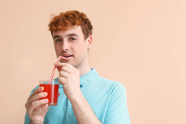 Fiatal férfi egy pohár vörös lé bézs háttér - Fotó, kép