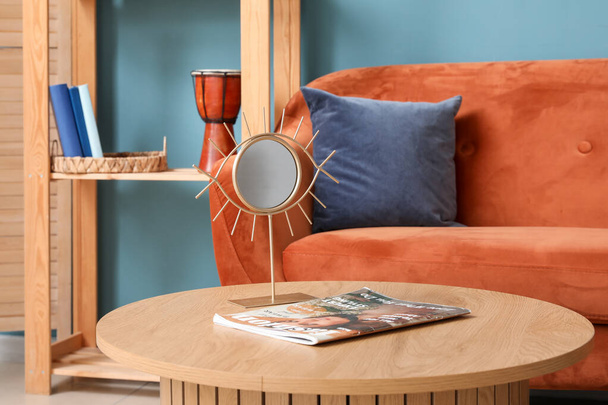 Innenraum des Wohnzimmers mit orangefarbenem Sofa und Spiegel auf Holztisch - Foto, Bild