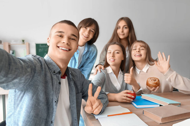 Grupo de estudiantes adolescentes tomando selfie en la mesa en el aula - Foto, Imagen