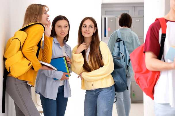 Teenage girls talking about classmate at school - Fotó, kép