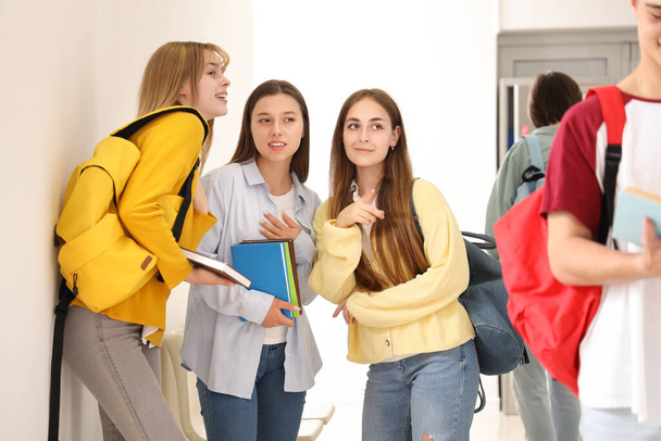 Teenagermädchen reden in der Schule über Mitschülerin - Foto, Bild