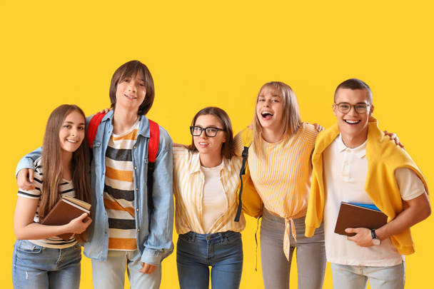 Group of teenage students on yellow background - Фото, изображение