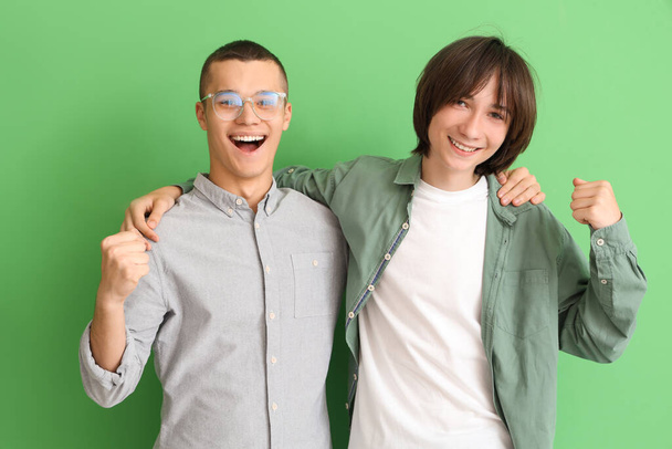 Happy male students hugging on green background - Photo, Image