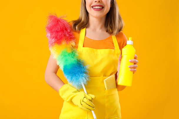 Mujer joven con botella de detergente y pp-duster sobre fondo naranja, primer plano - Foto, imagen