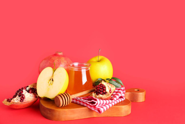 蜂蜜、ザクロ、りんごの瓶、赤い背景のロシュ・ハシャナーのお祝い(ユダヤの新年) - 写真・画像