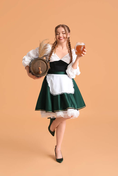 Όμορφη σερβιτόρα Octoberfest με μπύρα και βαρέλι σε μπεζ φόντο - Φωτογραφία, εικόνα