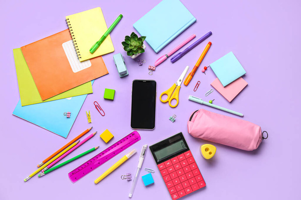 Different stationery with calculator and mobile phone on lilac background - Fotografie, Obrázek
