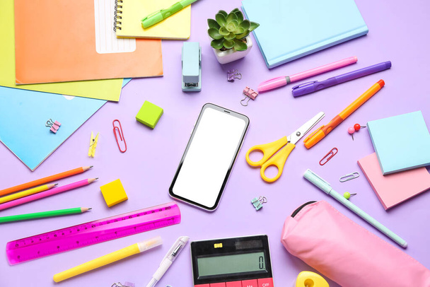 Different stationery with calculator and mobile phone on lilac background - Foto, afbeelding