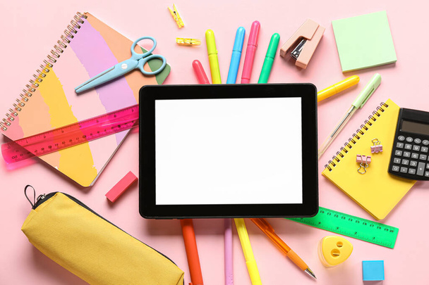 Различные канцелярские принадлежности с планшетом и калькулятором на розовом фоне - Фото, изображение