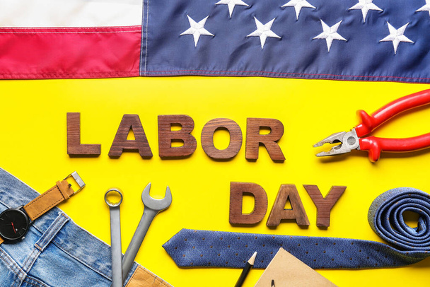 Composition avec différents outils, jeans, cravate, texte LABOR DAY et drapeau américain sur fond jaune - Photo, image