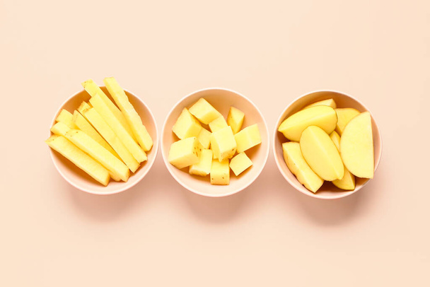 Bowls with pieces of raw potato on pink background - Photo, Image