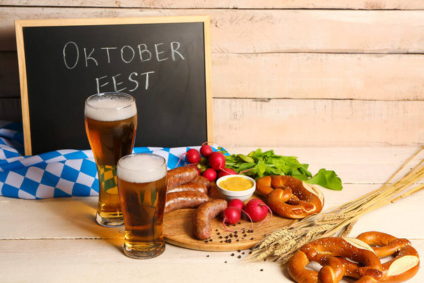 Bicchieri di birra fredda e piatto con diversi snack su sfondo di legno chiaro. Festa dell'Oktoberfest - Foto, immagini