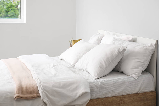 Large double bed with white pillows in interior of light bedroom - Foto, afbeelding