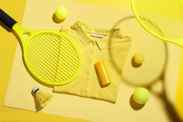 Samenstelling met stijlvol t-shirt, fles zonnebrandcrème en sportuitrusting op kleur achtergrond - Foto, afbeelding