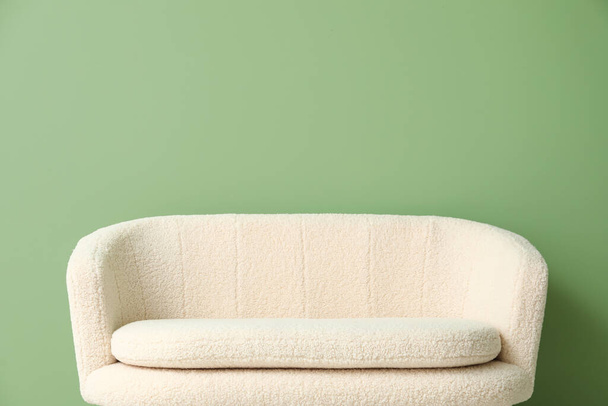 Άνετο λευκό καναπέ κοντά στο πράσινο τοίχο - Φωτογραφία, εικόνα
