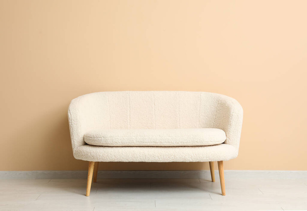 Cozy white sofa near beige wall - 写真・画像