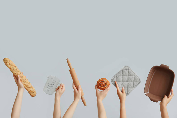Γυναικεία χέρια με μαγειρικά σκεύη και ζαχαροπλαστική σε γκρι φόντο - Φωτογραφία, εικόνα