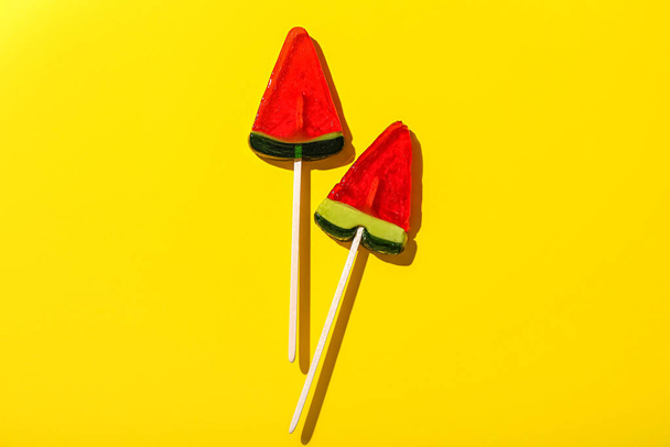 Lollipops in shape of watermelon slice on yellow background - 写真・画像
