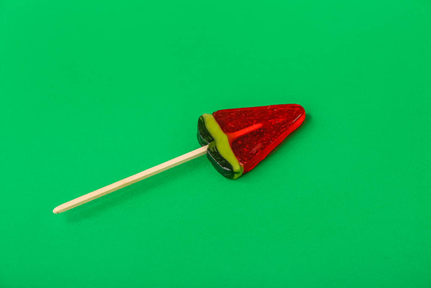 Lollipop in shape of watermelon slice on green background - Photo, Image