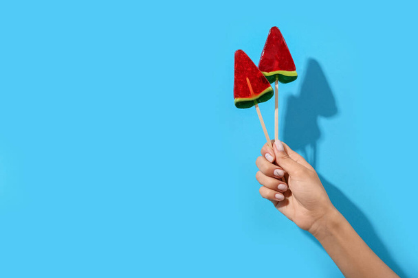 Woman holding lollipops in shape of watermelon slice on blue background - Photo, image