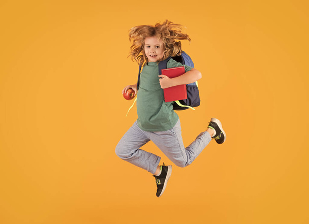 Täyspitkä runko pikku koulupoika hyppääminen hauskaa eristetty keltainen väri tausta. Hullu koulupoika hyppää - Valokuva, kuva