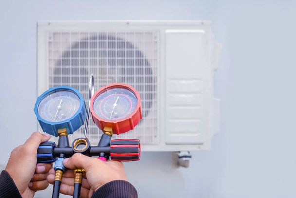 Air conditioning, HVAC service technician using gauges to check refrigerant and add refrigerant. - Photo, Image