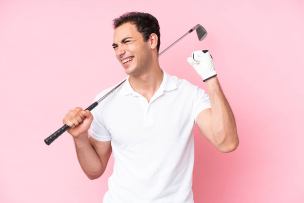 Νεαρός παίκτης του γκολφ απομονωμένος σε ροζ φόντο γιορτάζει μια νίκη - Φωτογραφία, εικόνα