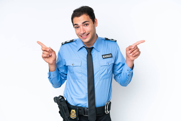 Молодий поліцейський кавказький чоловік ізольований на білому тлі, вказуючи пальцем до латералів і щасливий
 - Фото, зображення