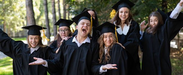 Група випускників в одязі вітає один одного з випуском на відкритому повітрі
 - Фото, зображення