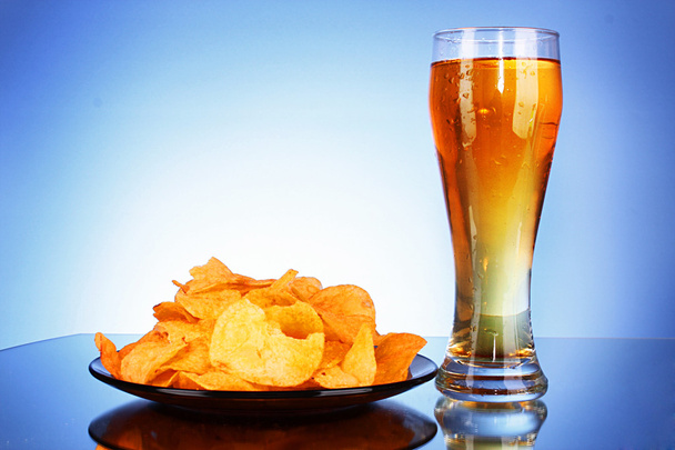 Beer and potato chips on blue background - Fotó, kép