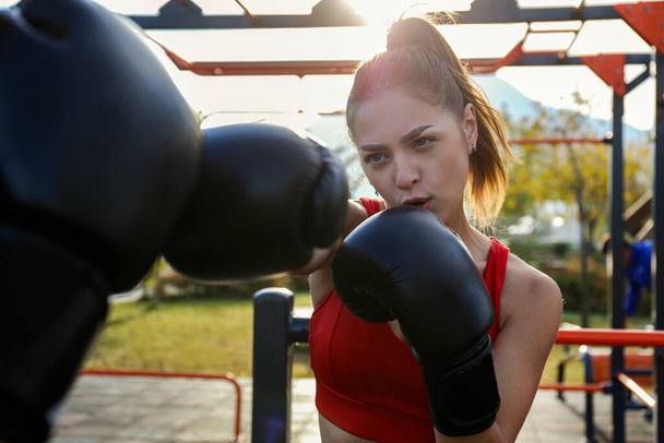 Female boxer practicing her moves at the park. Young woman training martial arts outdoors. Close up, copy space, background. - Φωτογραφία, εικόνα