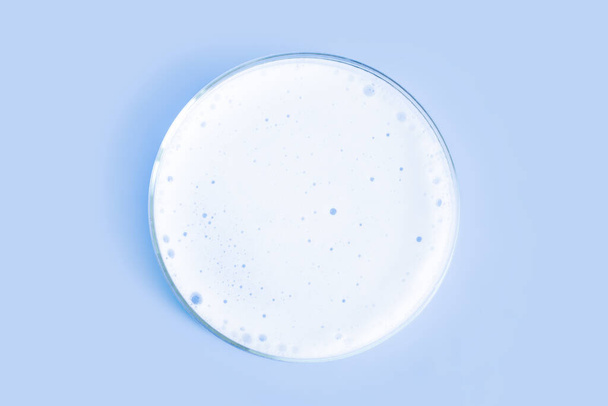Waschmittelschaum in einer Petrischale. Auf blauem Hintergrund. - Foto, Bild