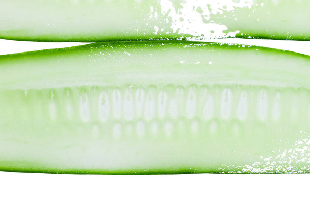 Vékonyan szeletelt, hosszában friss zöld uborka szeletek fehér alapon. - Fotó, kép