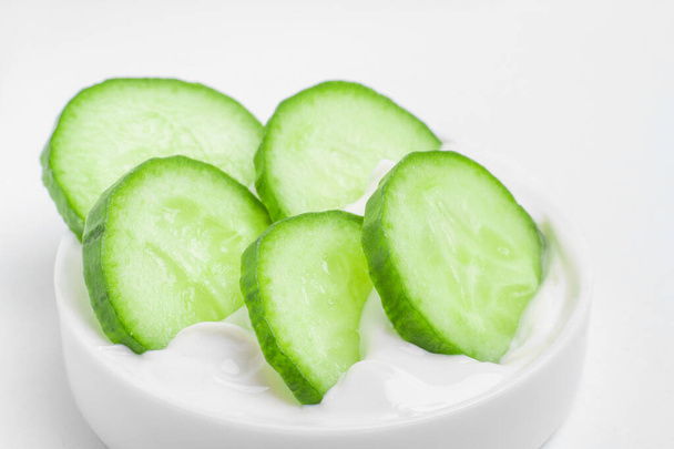 Slides of fresh cucumber in a jar of cream. On a white background.  - Photo, Image