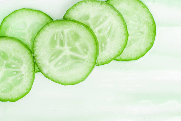 Slides of fresh cucumber on a cream smear. On a white background. - Photo, Image