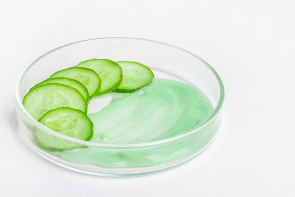 Dunne plakjes verse groene komkommer in een petrischaal. Een smeervet van groene komkommer room. - Foto, afbeelding