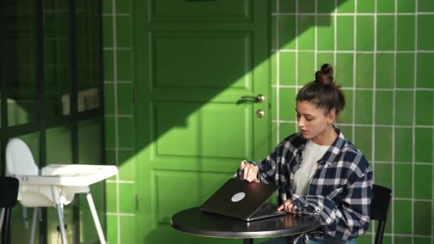 красивая молодая женщина сидит за столом с ноутбуком в кафе работает онлайн печатания. Высококачественные FullHD кадры - Кадры, видео